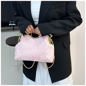 Detailed view of floral jacquard texture and golden frame on pink shell-shaped bag