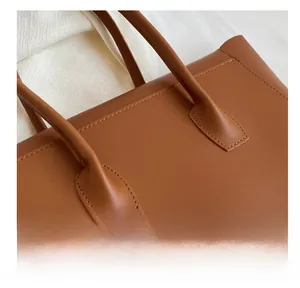 Detail of reinforced stitching and matte leather texture on brown tote bag handle