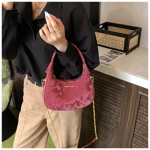 Detail of burgundy velvet crescent bag featuring gold chain and luxury velvet texture