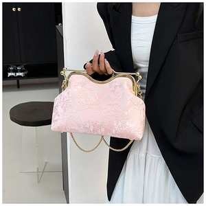 Detail of light pink shell bag featuring embossed floral texture and gold metal clasp