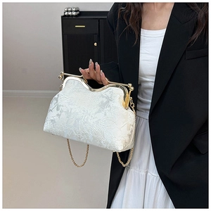 Close-up of elegant floral jacquard texture and gold metal clasp on a shell-shaped handbag