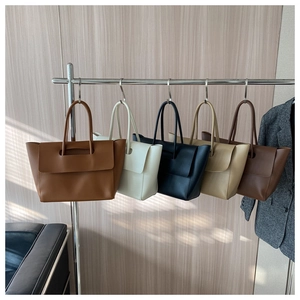 Fünf minimalistische Ledertaschen in den Farben Karamell, Creme, Schwarz und Beige am Bügel