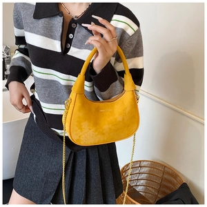 Detail of yellow velvet crescent bag featuring gold chain strap and branding