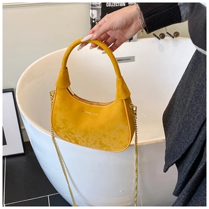 Close-up of bright yellow velvet crescent bag with gold chain and fashion lettering