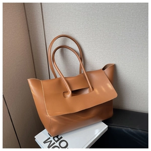 Detail of large brown faux leather tote bag with wide bottom and flap closure