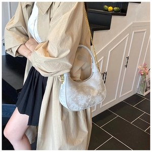 Detail of grey marble pattern velvet hobo bag with gold chain and handle in lifestyle setting