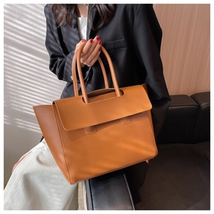 Detail of vintage brown leather tote bag held by a model in a sophisticated setting