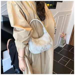 Detail of silver velvet crescent hobo bag with gold chain strap worn by a model
