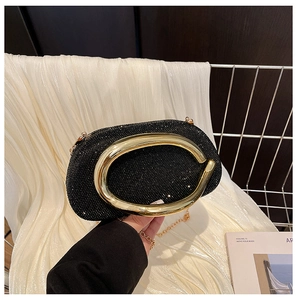 Detail of black rhinestone evening clutch with large gold C-ring handle and metal chain