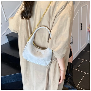 Detail of silver velvet crescent bag with chain strap and gold text logo