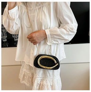 Close-up of black sequin evening bag featuring large gold oval buckle and chain strap
