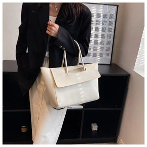 Detail of minimalist cream-white structured tote bag with slim handles and high gloss finish