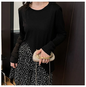 Detail of a gold sequin clutch bag with circular metal handle held by a model in a floral skirt