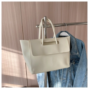 Detail view of cream white leather tote bag featuring unique cutout handle and long straps