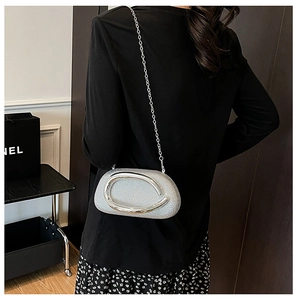 Silver sequin clutch bag with metal handle and chain strap on black background