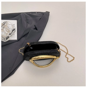 Detail of black rhinestone evening clutch bag with gold handle and metal chain strap