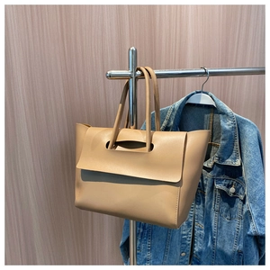 Detail view of large apricot tote bag with unique cut-out flap on stainless steel hanger