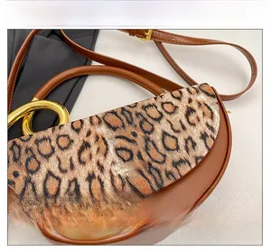 Detail of leopard print suede flap and golden ring handle on brown leather handbag