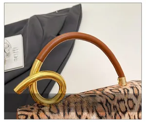 Detail of leopard print fabric handbag with brown leather and gold metal knot handle