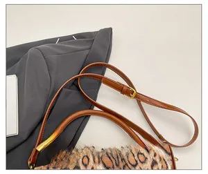 Detail of leopard print handbag with brown leather strap and golden circular buckle
