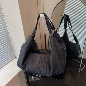 Minimalist black large capacity pleated shoulder bag with textured fabric and metal rings