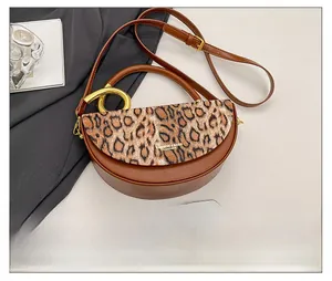 Detail of brown leopard print half-moon bag with gold handle and phone for size scale