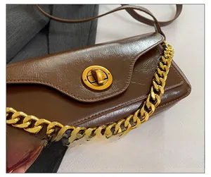 Close-up of brown glossy mini bag showing the gold chain detail and round twist lock