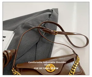 Detail of adjustable leather strap and decorative gold metal chain on brown vintage bag
