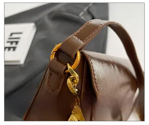 Macro detail of glossy brown oil wax leather and bold gold chain link with buckle