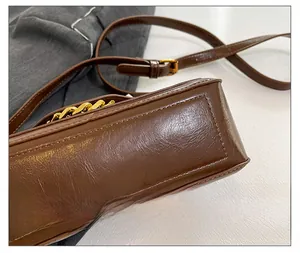 Detailed view of meticulous stitching and gold chain on brown vintage leather bag