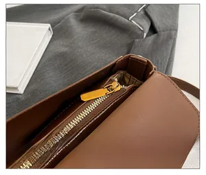 Detailed close-up of smooth gold zipper on dark brown stone pattern handbag with lining
