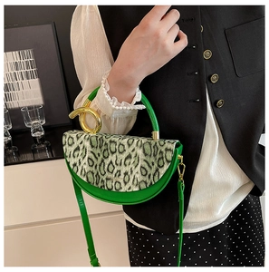 Detail of green crescent handbag with leopard print flap and gold ring handle