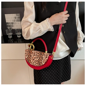 Red half-moon handbag with leopard print flap and gold clasp shown on a model