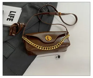Detailed view of brown leather shoulder bag with gold chain and size reference to phone