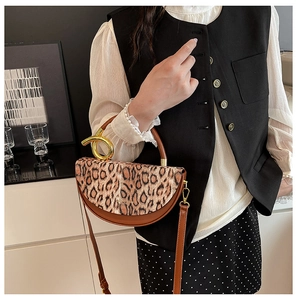 Detailed close-up of leopard print bag with artistic gold circular metal handle