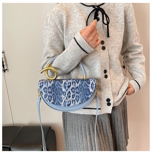 Detail of blue leopard print handbag with a unique golden spiral handle and leather strap