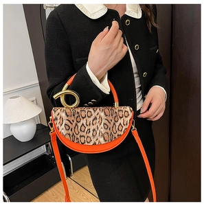 Detail of orange crescent handbag with leopard print flap and golden twisted metal handle