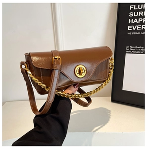 Detail of a brown leather shoulder bag with a gold buckle and decorative chain