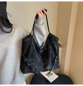 Détail du sac cabas en similicuir noir avec texture vintage et boucle argentée
