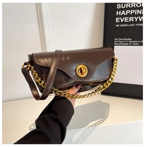 Detail of vintage chocolate brown shoulder bag with shiny faux leather and gold buckle