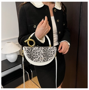 Close-up of golden twisted buckle and leopard print flap on white leather handbag