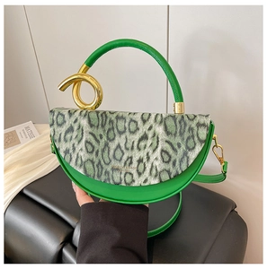 Detail of green faux leather handbag with leopard print flap and gold metal hardware