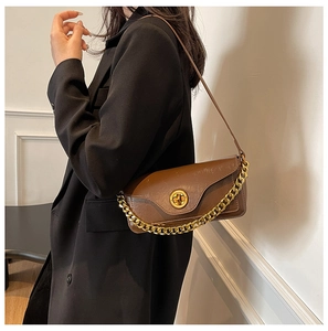 Detail of dark brown retro shoulder bag featuring a matte finish and gold twist lock