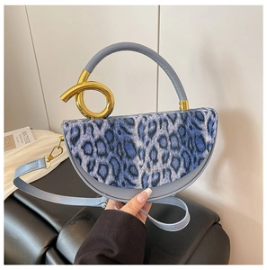 Close-up of leopard print handbag with twisted golden metal ring handle and blue strap