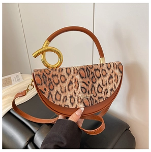 Detail of leopard print flap and gold circular handle on a brown leather handbag