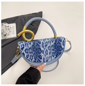 Detail view of blue leopard print box bag with luxury gold twisted metal handle