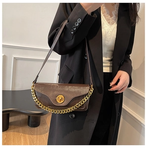 Close-up of a vintage dark brown leather shoulder bag with gold clasp and chain strap