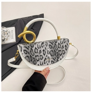 Detail of leopard print faux fur flap and gold knot handle on a mini white leather bag