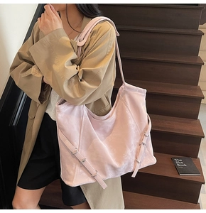 Gros plan sur un grand sac porté épaule rose avec sangles sur un escalier en bois