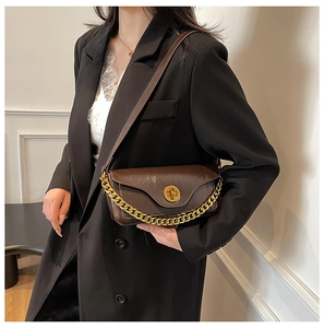 Detail of vintage brown shoulder bag featuring chunky gold chain and metallic twist lock